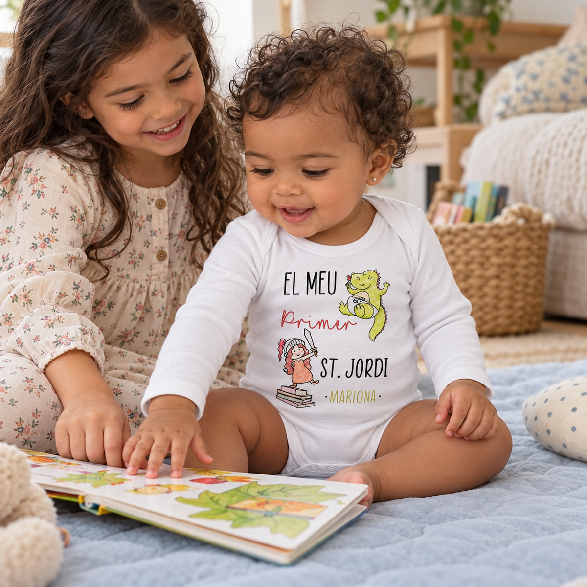 Bebé con body Primer Sant Jordi Princesa y nombre Mariona mirando un libro con su hermana