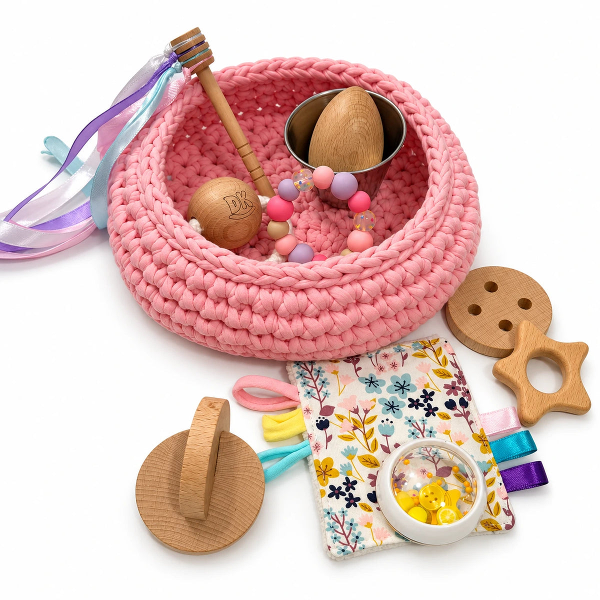 Cesto de los tesoros Blush Pink de trapillo rosa: detalle del cesto, el trapito y los accesorios sensoriales.