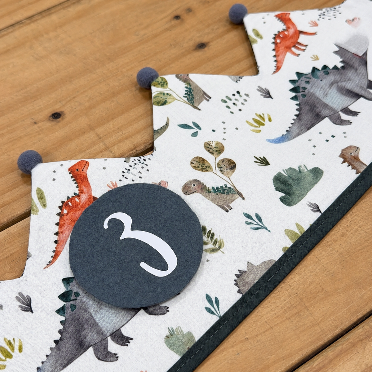 Corona Dinos extendida sobre madera: detalle del estampado y del número