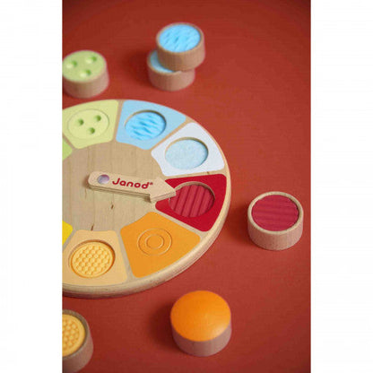 Detalle de la ruleta y piezas táctiles sobre fondo rojo — Janod