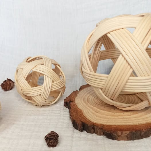 Pelotas Pikler de dos tamaños juntas sobre fondo textil y base de madera