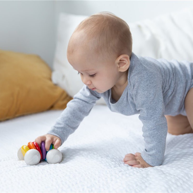 JUGUETE DE MADERA PLAN TOYS ·COCHÉ BEBÉ ARCOÍRIS· - Happy Moments Baby